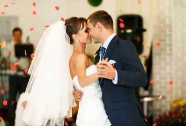 Ein Hochzeitspärchen beim Tanzen mit roten Rosen als Regen.
